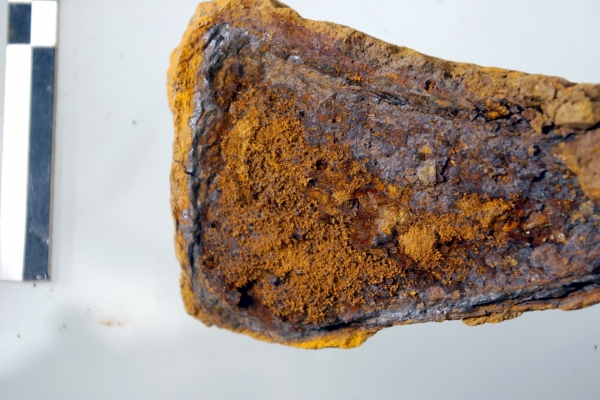 Detail Merovingische bijl: losse oranje kristallen hebben de bijl uit elkaar geduwd. © SPW-Archéologie