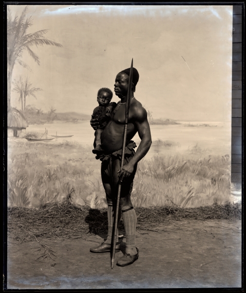 Koloniale propagandafoto. Congolese man met kind voor een geschilderd decor © Collectie MAS (AE.1963.0063.0023.D)