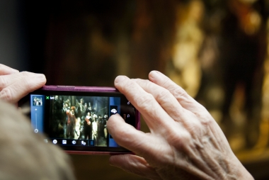 René den Engelsman, Bezoeker fotografeert de Nachtwacht met een digitale camera, 2013. Publiek domein via Rijksstudio.