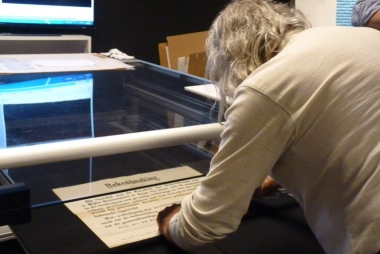 Een vrijwilliger helpt bij het inscannen van tekstaffiches in het Stadsarchief Gent (c) Stadsarchief Gent