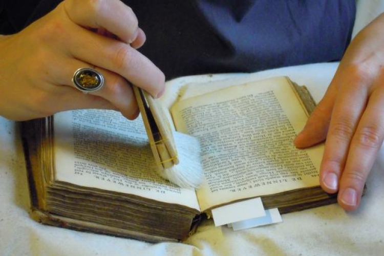 Droog reinigen van een boek met behulp van een Japanse borstel. Foto: © DIVA. Museum voor Edelsmeedkunst, Juwelen en Diamant te Antwerpen