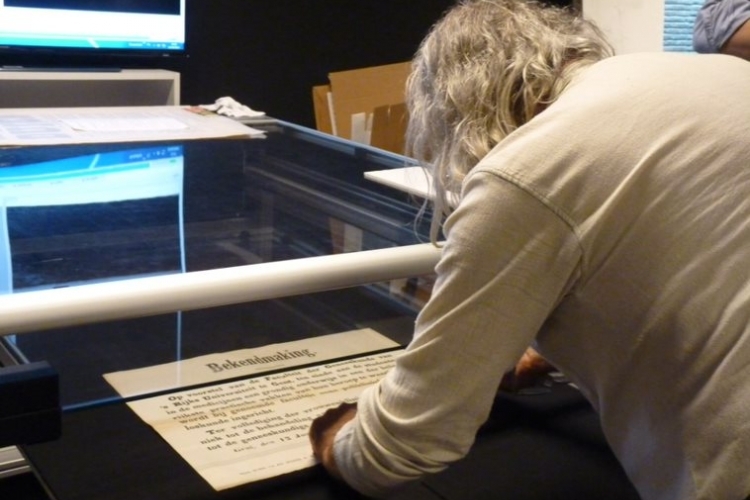 Een vrijwilliger helpt bij het inscannen van tekstaffiches in het Stadsarchief Gent (c) Stadsarchief Gent.
